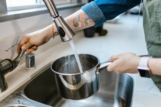 Filling a bottle with filtered water at a kitchen sink