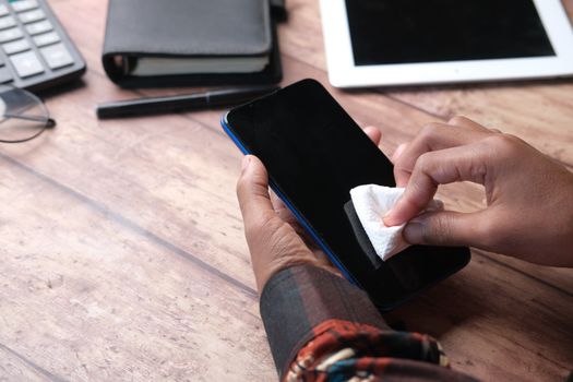 Person wiping down a smartphone with a soft cloth