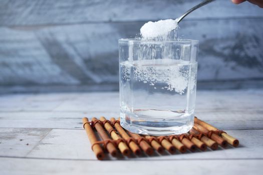 Spoon pouring powder supplement into a glass of water