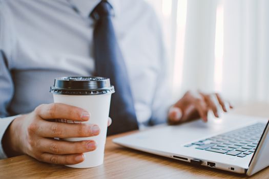 Person working at a laptop with coffee nearby in the morning