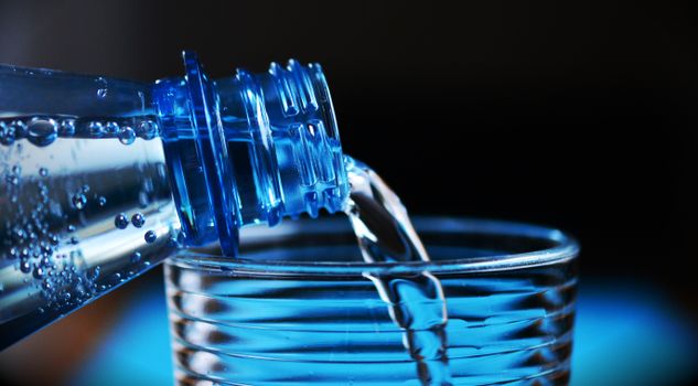 Pouring carbonated water from a bottle into a glass