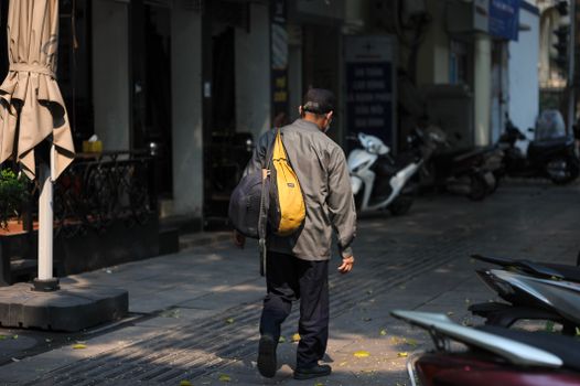 Person walking away down a street carrying a bag