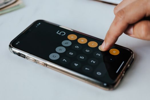 Person calculating cost per use on a phone