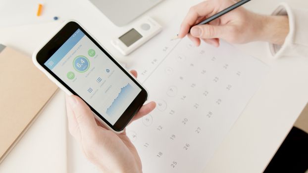 Person tracking notes on a phone at a desk