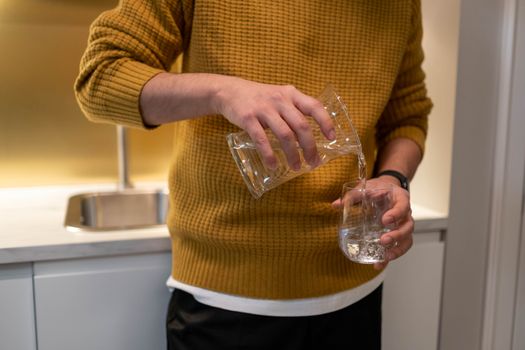 Person pouring a glass of water in a kitchen