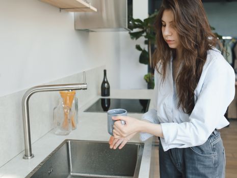 Person filling a hydrogen water bottle at a kitchen sink