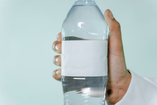Close-up of a hand holding a water bottle with a blank label