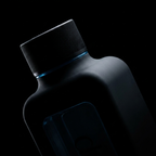 Macro crop of the upper half of the Hydrator Max, matte black neck and cap with a blue rim highlight on a near-black studio background.